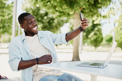 Side view of man using mobile phone while sitting on table