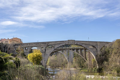 Arch bridge over river against sky