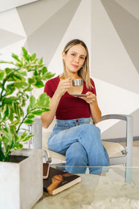 Portrait of young woman using mobile phone while sitting outdoors