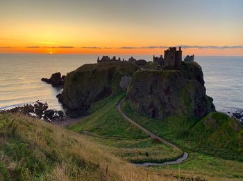 Scenic view of cast against sky and sea during sunrise