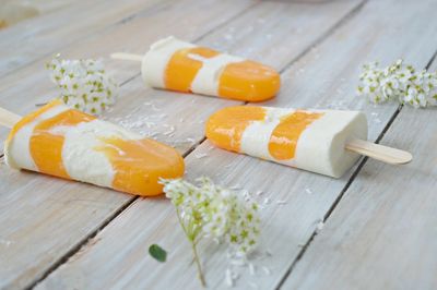 Close-up of popsicles with flowers on wooden table