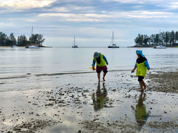 Rear view of men on beach against sky