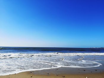 Scenic view of beach against clear blue sky