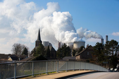 Smoke emitting from factory against sky