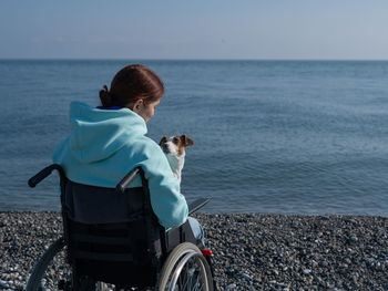 Disabled woman with dog against sea