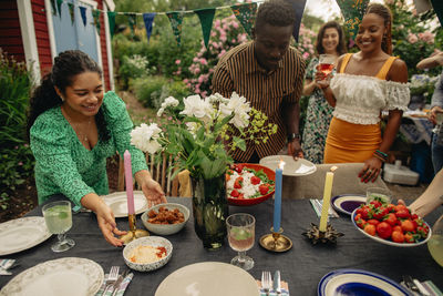 Male and female friends setting up table during garden party