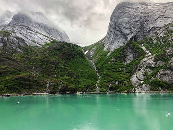 Breathtaking mountains  with waterfalls that tumble down to the emerald green water.