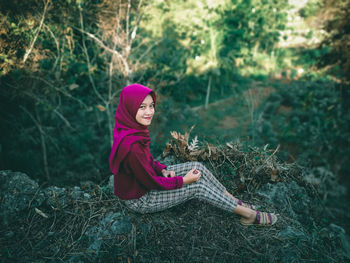 Portrait of woman sitting on rock