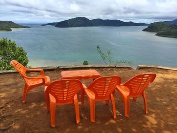 Chairs and table on beach against sky