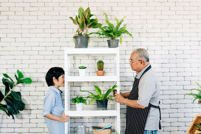 Side view of people standing by potted plants