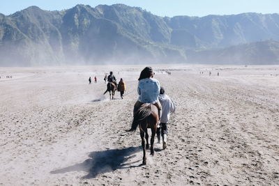 Rear view of people riding horses at bromo-tengger-semeru national park
