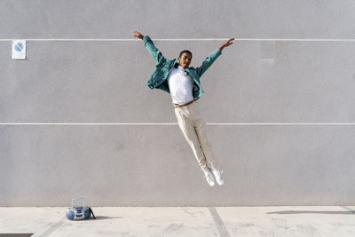 Full length of man jumping in concrete wall