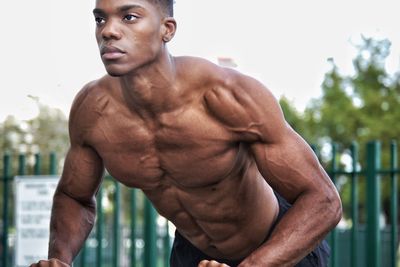 Midsection of shirtless man looking at camera