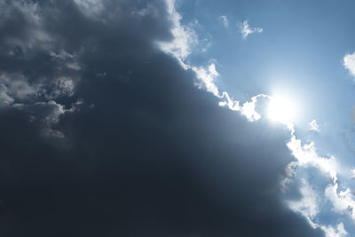 Low angle view of sunlight streaming through clouds