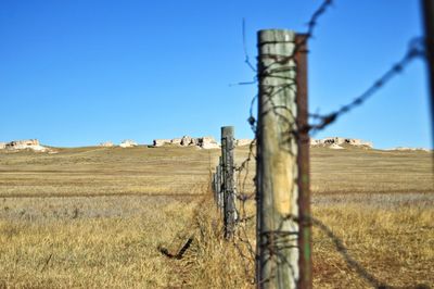 Fence on pasture against clear sky