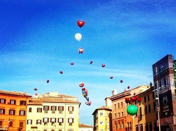 Low angle view of multi colored balloons against blue sky