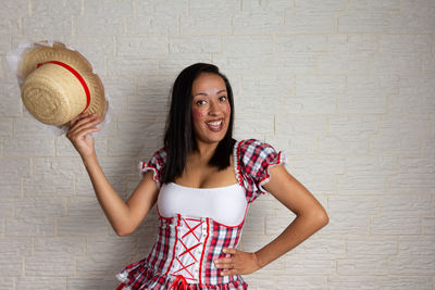 Portrait of smiling young woman standing against wall