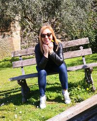 Portrait of young woman sitting on bench in park