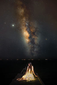 Woman against illuminated star field against sky at night