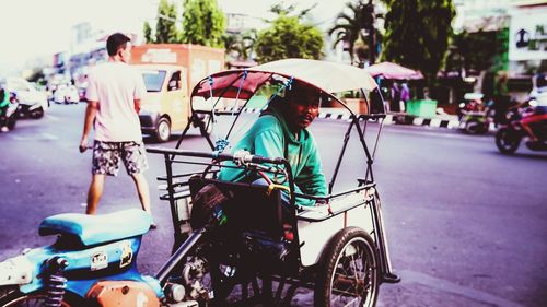 People on road by street in city