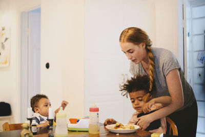 Toddler looking at mother giving food to brother at home