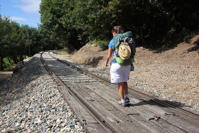 Rear view of boy standing on railroad track