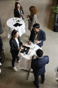 Business delegates discussing while standing at tables in convention center