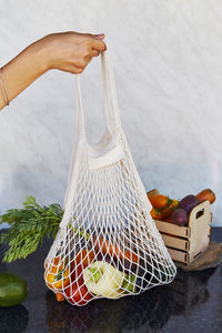 Woman holds eco shopping reusable bag full of fresh vegetables - tomatoes, purple potatoes, carrots
