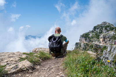 Rear view of a man standing on rock against sky