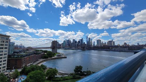 City by river and buildings against sky
