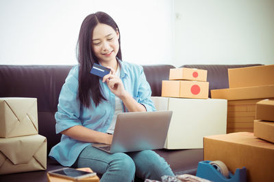 Young woman using phone while sitting on sofa