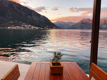 Swimming pool by lake against sky during sunset