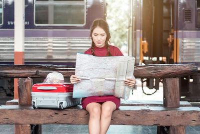 Portrait of young woman using mobile phone while sitting on roof