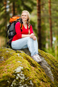 Portrait of woman sitting on rock in forest