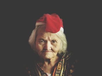 Portrait of senior woman in santa hat against black background