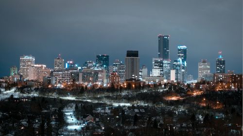 Illuminated buildings in city against sky at night