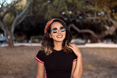 Portrait of smiling young woman wearing sunglasses standing outdoors