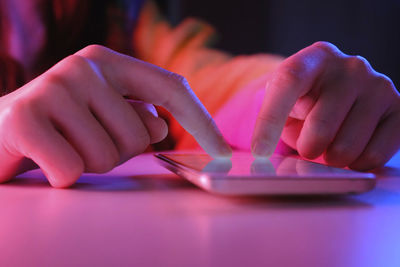 Use of mobile phone in trendy neon lights. creative vivid color of ultraviolet red and blue. hands