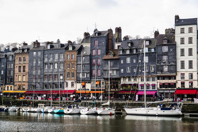 Boats in canal by buildings against sky