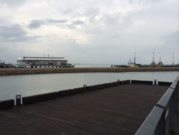 Pier on sea against cloudy sky