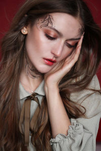 Close-up of woman looking down against red background