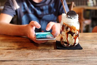 Midsection of person using mobile phone on table