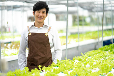 Portrait of young woman standing by plants