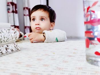 Cute baby boy at table in home