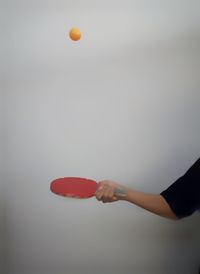 Cropped hand of woman playing table tennis against gray background