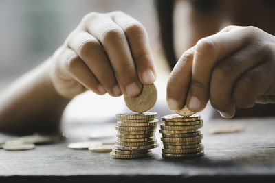 Close-up of hand holding coins over table