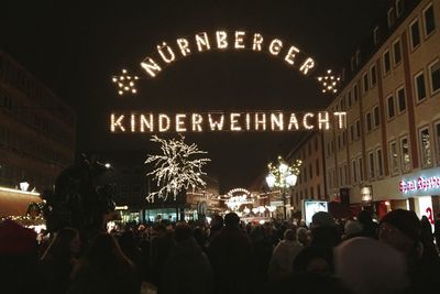 People on illuminated christmas tree at night