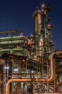 Illuminated factory against clear sky at night
