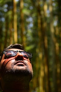 Young man wearing eyeglasses while looking away in forest