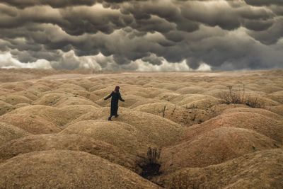 Rear view of man standing on land against sky